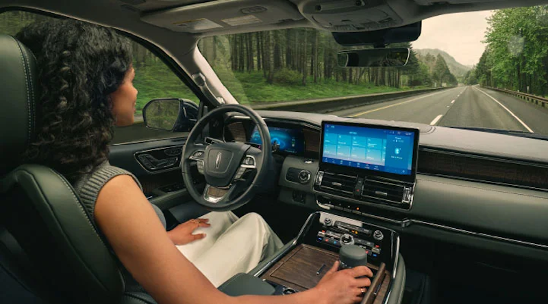 A woman sitting behind the wheel of a 2024 Lincoln vehicle and looking at the technology-filled dashboard