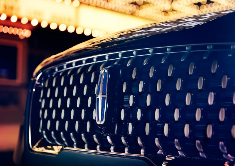 The Corsair Grand Touring grille shows floating chrome ovals that catch the glowing light of a theater marquee and frame the distinctive Lincoln Star | Bob Maxey Lincoln in Detroit MI