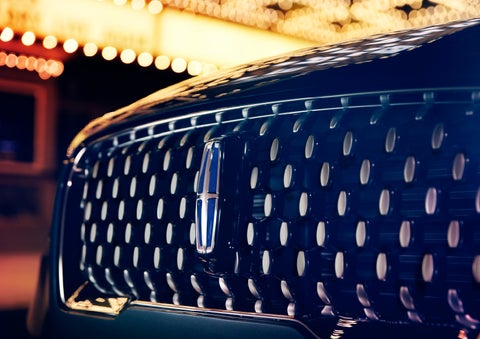 The Corsair Grand Touring grille shows floating chrome ovals that catch the glowing light of a theater marquee and frame the distinctive Lincoln Star | Bob Maxey Lincoln in Detroit MI