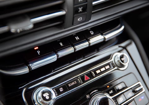 The Park button on the elegant Piano Key Shifter is lit up and engaged as light dances off the chrome accents and horizontal design lines | Bob Maxey Lincoln in Detroit MI