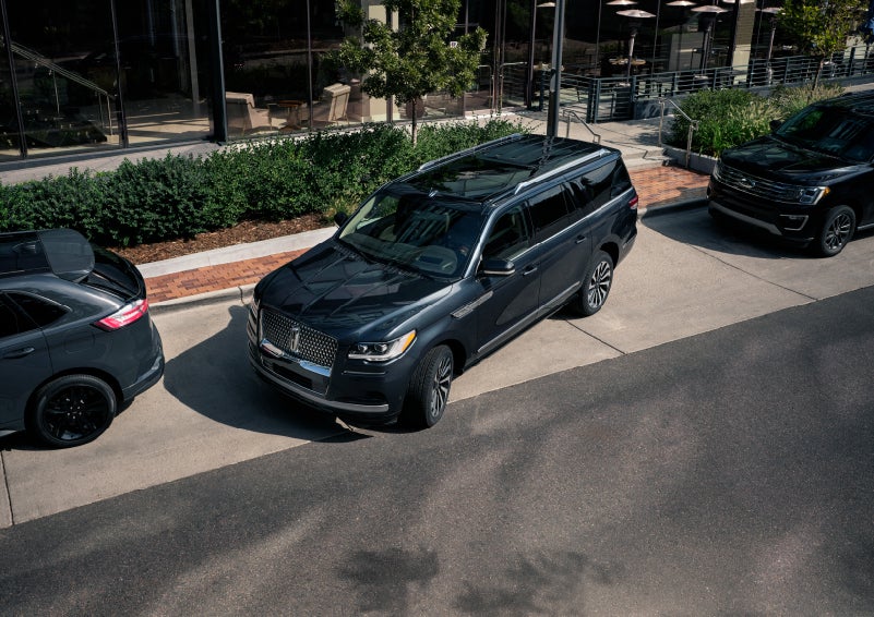 A 2022 Lincoln Navigator SUV is being parallel parked between two vehicles on a downtown street outside of a luxury hotel | Bob Maxey Lincoln in Detroit MI