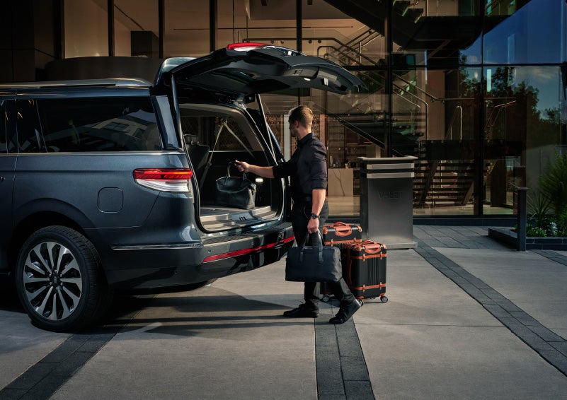 A valet is unloading luggage from the rear cargo area of a 2022 Lincoln Navigator SUV | Bob Maxey Lincoln in Detroit MI