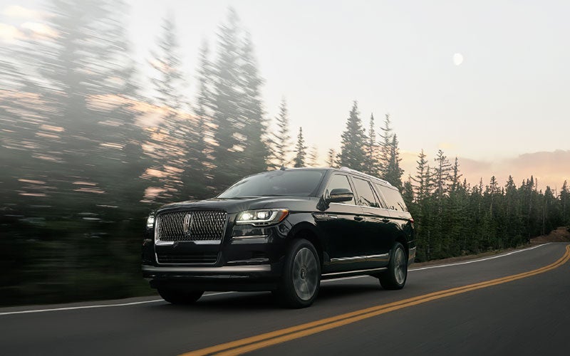A 2022 Lincoln Navigator SUV is driving along a mountain road with grounding power