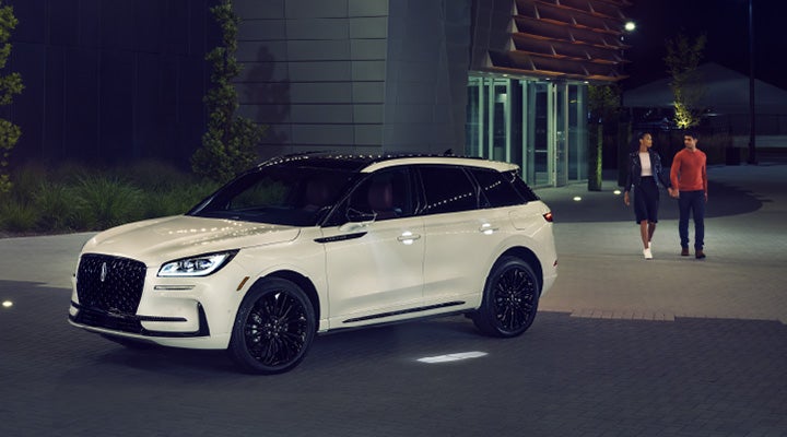 Two people approach a 2025 Lincoln Corsair® SUV featuring the available Jet Appearance Package.