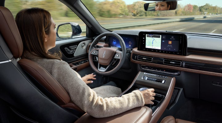 A 2026 Lincoln Aviator® SUV is being driven hands-free on a highway near a forest | Bob Maxey Lincoln in Detroit MI