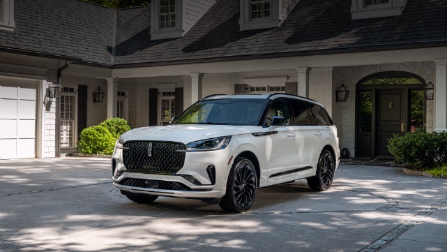 A white 2026 Lincoln Aviator® SUV is parked in the driveway of a luxury home. | Bob Maxey Lincoln in Detroit MI
