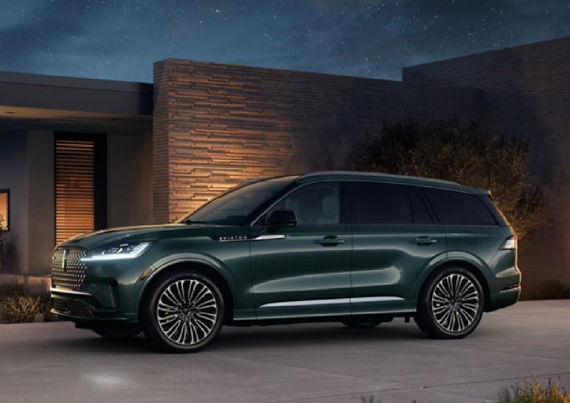 A green 2027 Lincoln Aviator® SUV is parked outside a contemporary home. | Bob Maxey Lincoln in Detroit MI