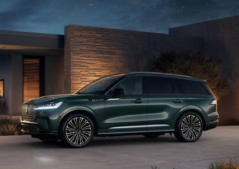 A green 2027 Lincoln Aviator® SUV is parked outside a contemporary home. | Bob Maxey Lincoln in Detroit MI