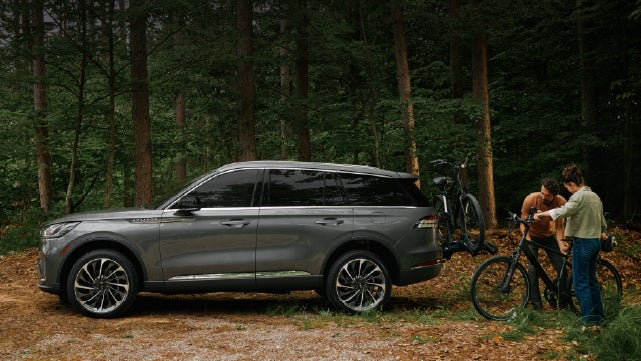 A father and son load e-bikes on a bike rack attached to a 2027 Lincoln Aviator® SUV. | Bob Maxey Lincoln in Detroit MI