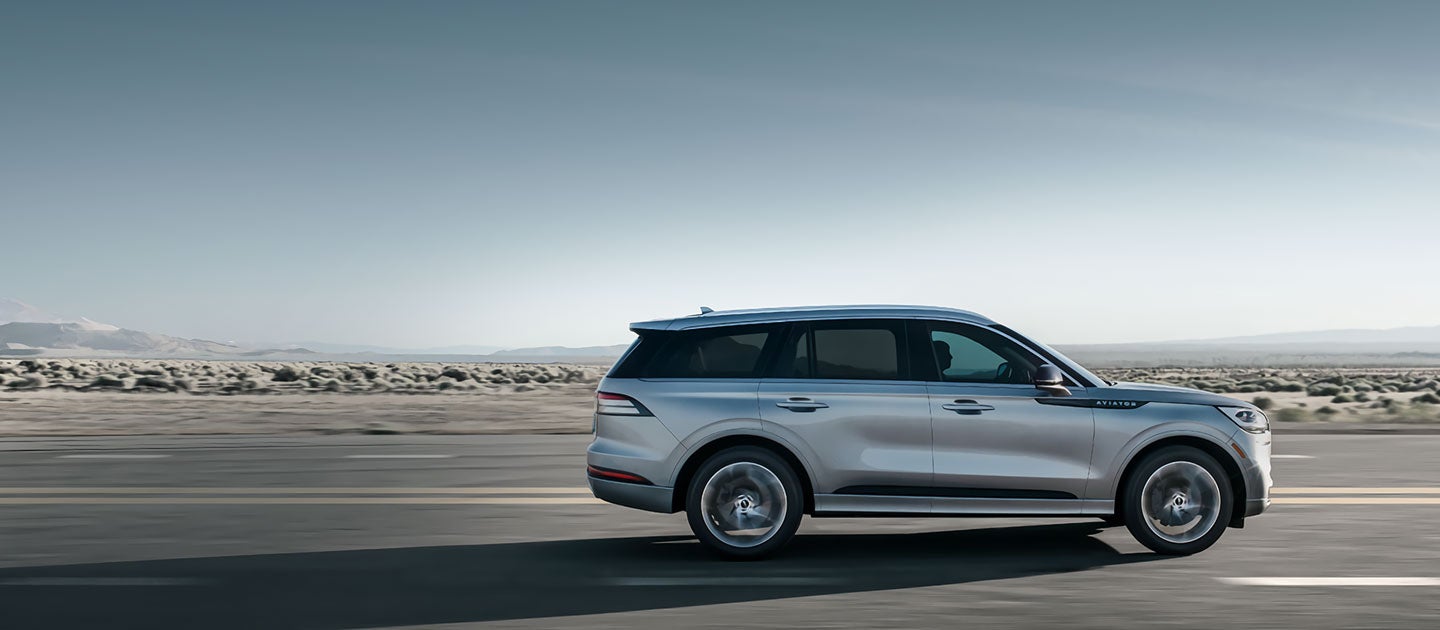 A 2020 Lincoln Aviator is shown being driven along a highway.