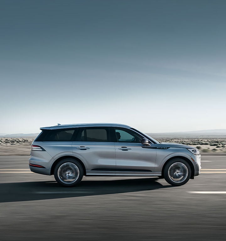A 2020 Lincoln Aviator is shown being driven along a highway.