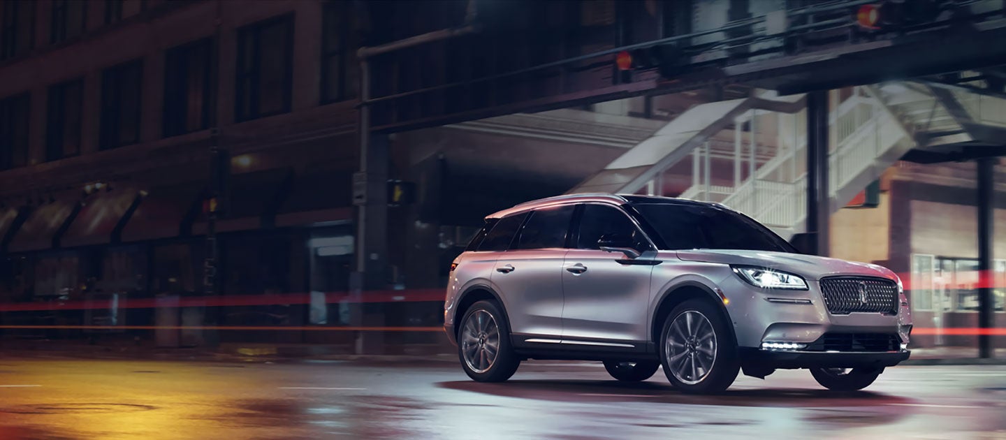A Lincoln Corsair is shown being driven on a city street at night