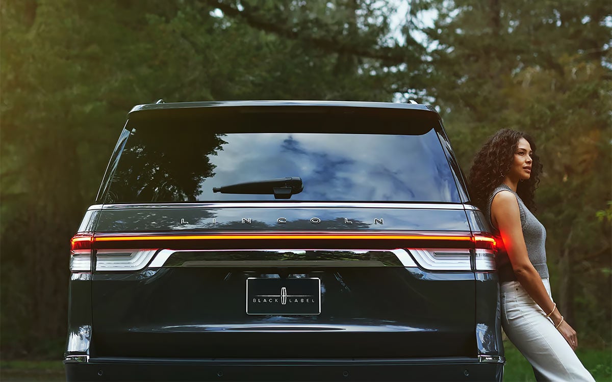 A woman leaning against the Lincoln Navigator<sup>&reg;</sup> SUV.