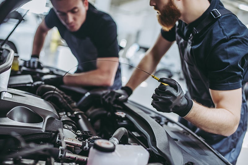 Mechanics inspecting a car engine in an auto repair shop.